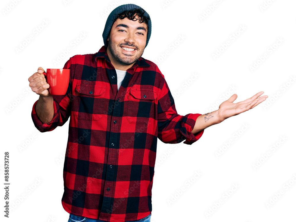 Hispanic young man with beard drinking a cup of coffee celebrating achievement with happy smile and winner expression with raised hand Hispanic young man with beard drinking a cup of coffee celebrating achievement with happy smile and winner expression with raised hand