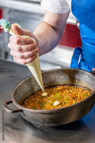 Chef prepara una paella en una paellera de hierro fundido en un restaurante photo