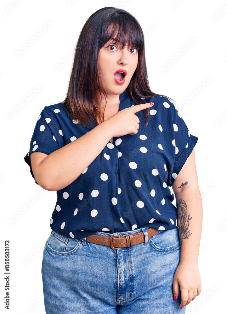 Φωτογραφία Young plus size woman wearing casual clothes surprised pointing with finger to the side, open mouth amazed expression