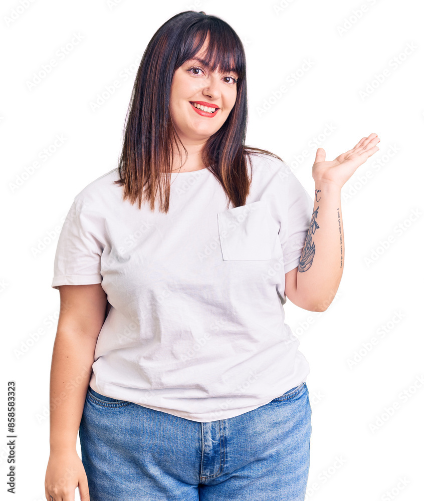 Young plus size woman wearing casual clothes smiling cheerful presenting and pointing with palm of hand looking at the camera. Young plus size woman wearing casual clothes smiling cheerful presenting and pointing with palm of hand looking at the camera.