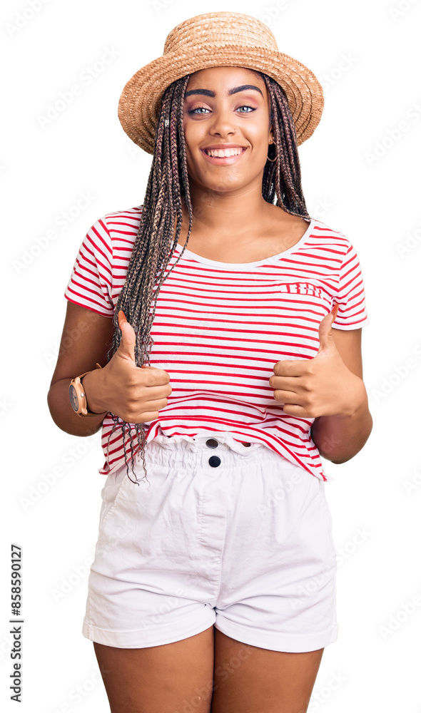 © Krakenimages.com - Young african american woman with braids wearing summer hat success sign doing positive gesture with hand, thumbs up smiling and happy. cheerful expression and winner gesture.