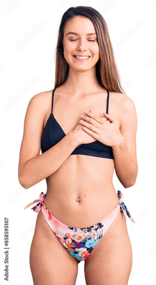 Young beautiful girl wearing bikini smiling with hands on chest with closed eyes and grateful gesture on face. health concept. Young beautiful girl wearing bikini smiling with hands on chest with closed eyes and grateful gesture on face. health concept.