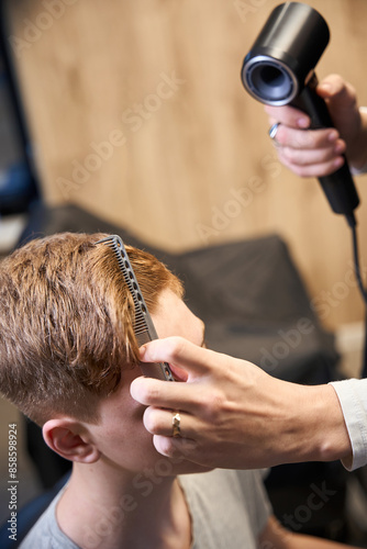 Experienced barber serving visitor in modern hairdressing salon