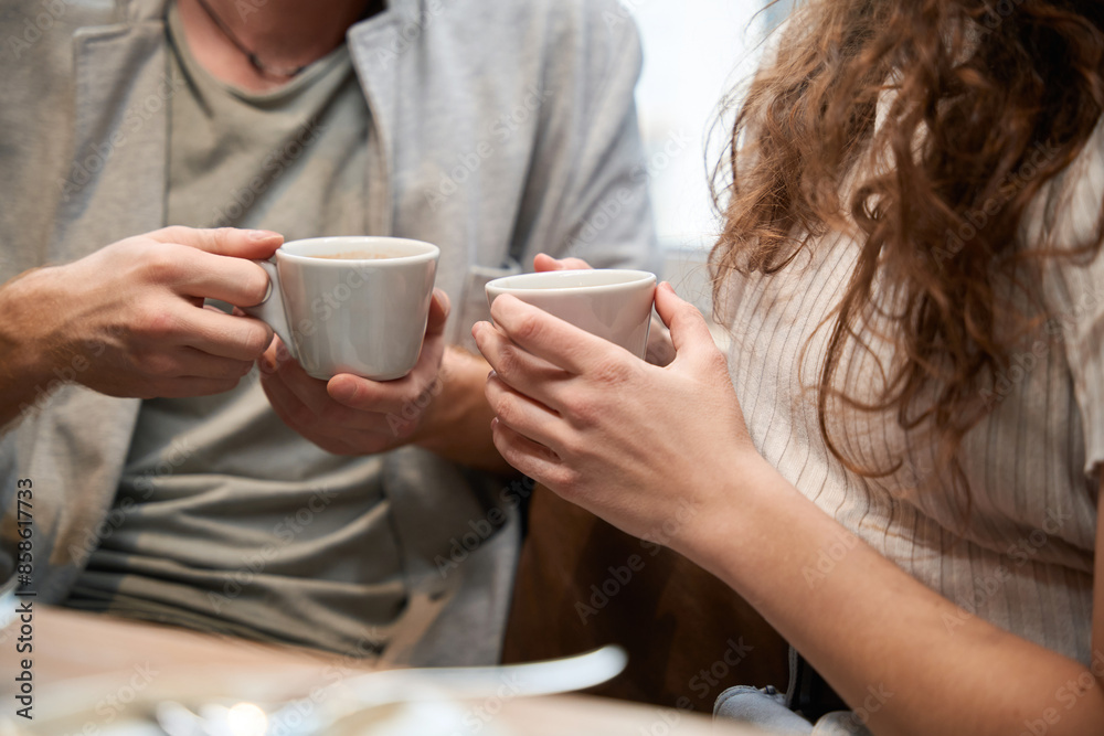 Couple is sitting in a restaurant holding coffee in their hands Couple is sitting in a restaurant holding coffee in their hands
