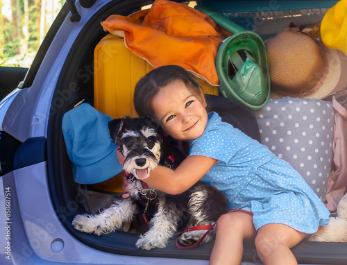 Portrait of a child with a schnauzer dog in the trunk of a car ready for vacation