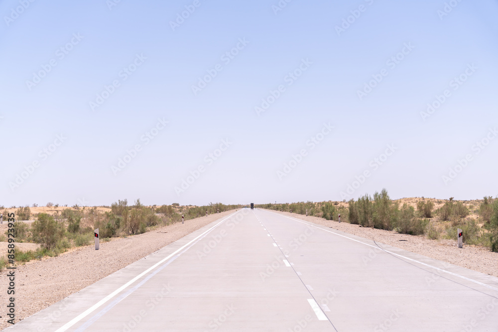 A long, empty road with no cars or people. The sky is clear and blue. The road is made of concrete and is very wide A long, empty road with no cars or people. The sky is clear and blue. The road is made of concrete and is very wide