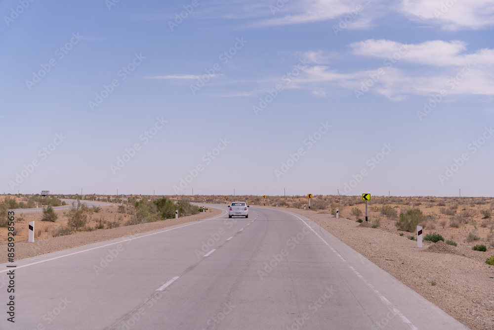 A car is driving down a road in a desert. The road is empty and there are no other cars or people in the scene. The sky is clear and the sun is shining brightly A car is driving down a road in a desert. The road is empty and there are no other cars or people in the scene. The sky is clear and the sun is shining brightly