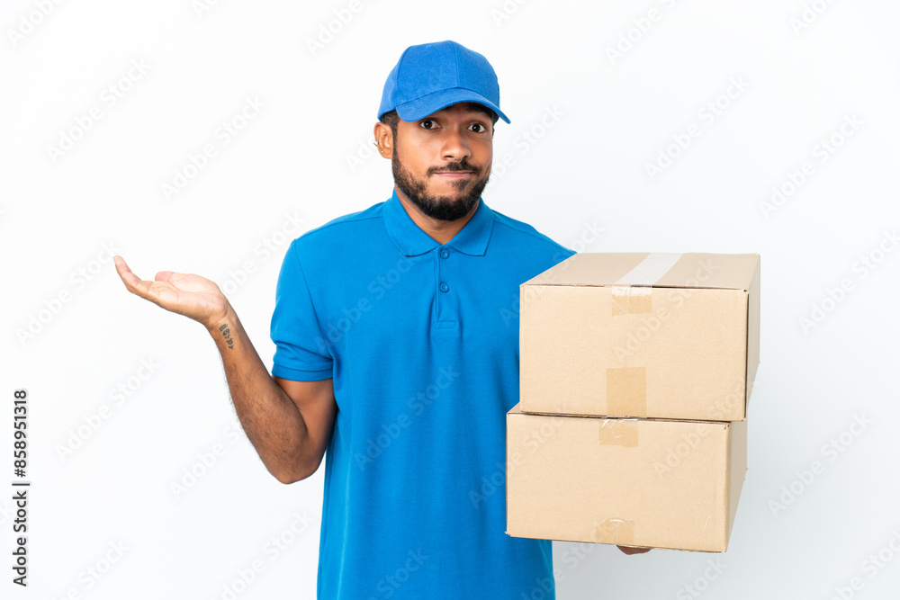 Delivery Ecuadorian man isolated on white background having doubts while raising hands Delivery Ecuadorian man isolated on white background having doubts while raising hands