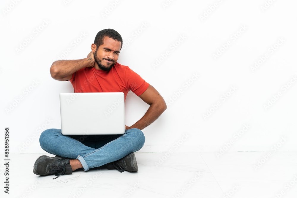 Young Ecuadorian man with a laptop sitting on the floor isolated on white background with neckache Young Ecuadorian man with a laptop sitting on the floor isolated on white background with neckache