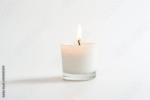 Single White Candle Burning in Glass Jar on White Background