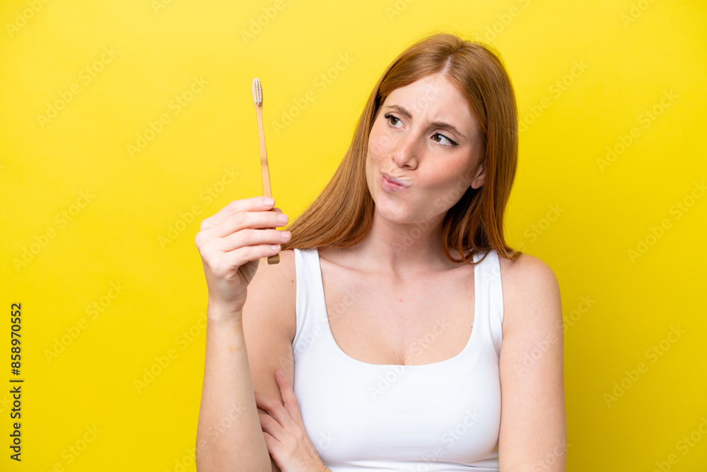 Young redhead woman brushing teeth with sad expression Young redhead woman brushing teeth with sad expression