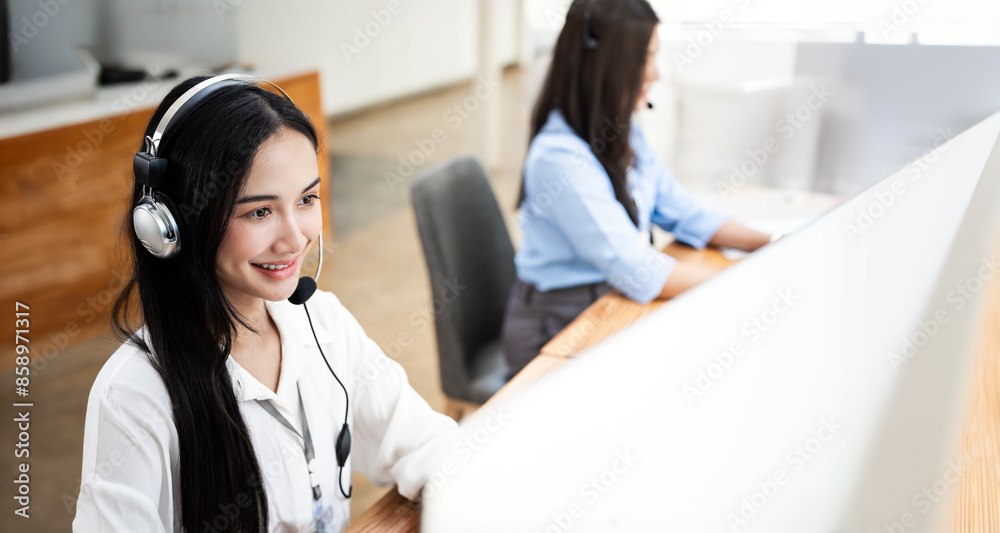 Asian businesswoman using a headset working with her colleague at office. Asian businesswoman using a headset working with her colleague at office.