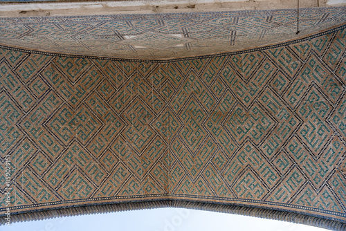 A building with a green and brown patterned wall. The pattern is made up of squares and triangles, and the wall is covered in a variety of colors. Scene is one of warmth and comfort photo