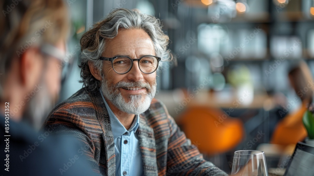positive middle aged business man with glasses and beard in office smiling discussing with colleagues at lunch