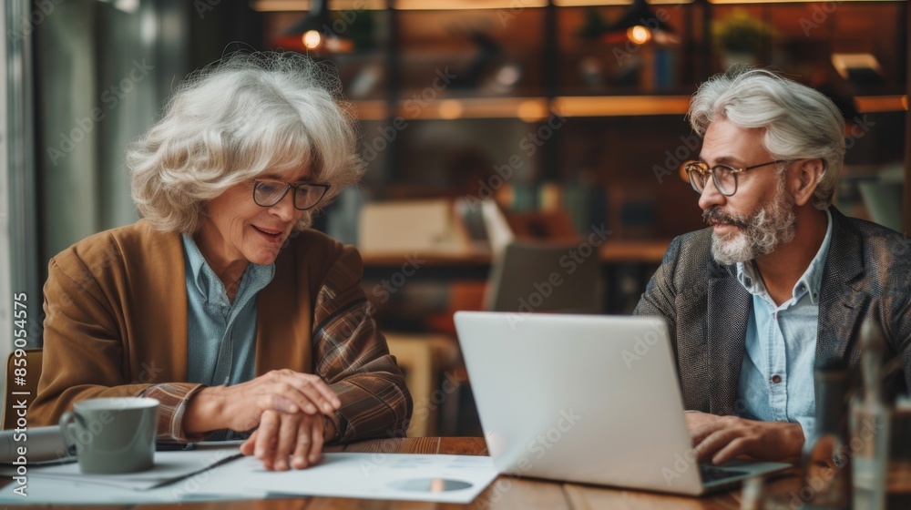Caucasian middle aged man and woman at work in office consulting working together on laptop, teamwork, on-the-job training Caucasian middle aged man and woman at work in office consulting working together on laptop, teamwork, on-the-job training