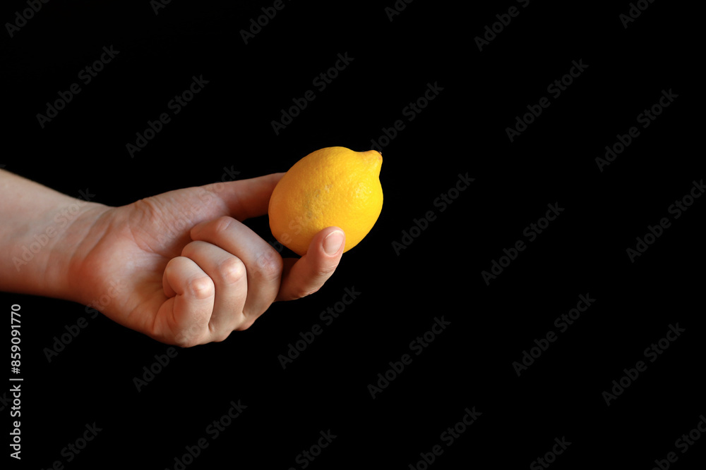 Close-up of a woman's hand holding a ripe lemon. Yellow lemon in hand on a black background. Ingredient. Fruit and food concept. Citrus Close-up of a woman's hand holding a ripe lemon. Yellow lemon in hand on a black background. Ingredient. Fruit and food concept. Citrus