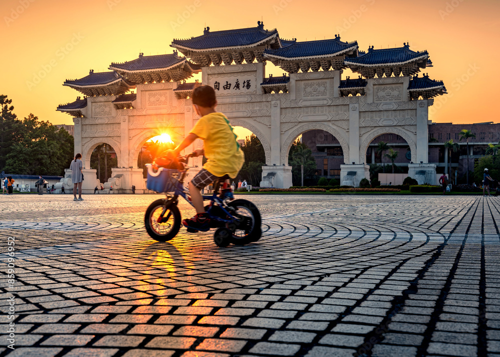 Naklejka premium child cycling in front of Liberty Square Arch taipei