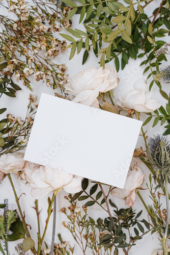 Elegant Floral Background with White Roses, Wildflowers and Petals. Blank White Paper Surrounded by Soft Delicate Flowers
