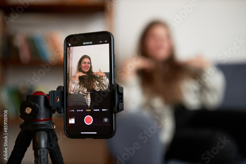 Selective focus on smartphone screen recording plus size blogger influencer on couch streaming live with her subscribers, sharing advice upon losing weight, healthy eating and stories of her life