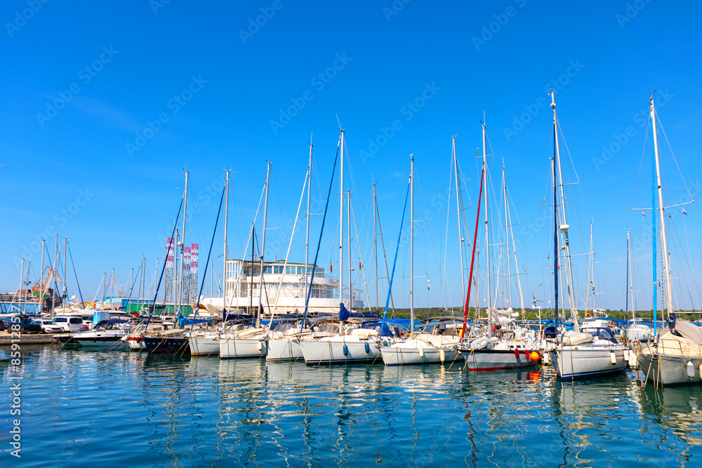 Sailboats are moored at the harbor. Boats docked at a marina with calm water Sailboats are moored at the harbor. Boats docked at a marina with calm water