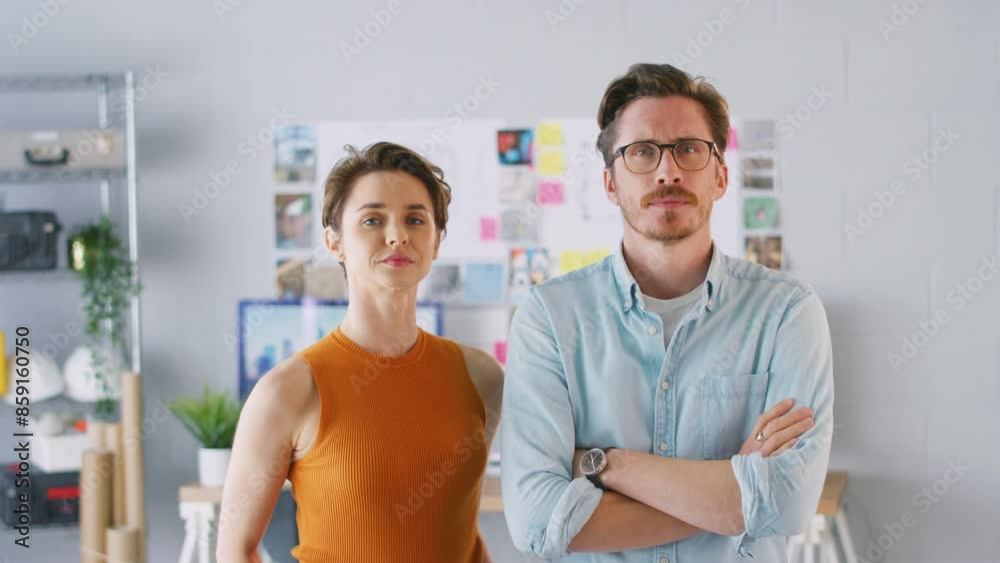 Camera tracks across frame as casually dressed architect works at desk in office before looking up and smiling into camera- shot in slow motion Camera tracks across frame as casually dressed architect works at desk in office before looking up and smiling into camera- shot in slow motion
