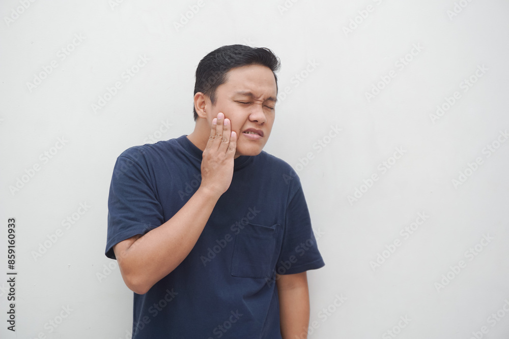 Man suffering from toot ache isolated on white. Young Asian man touching his jaw with pain expression. Man suffering from toot ache isolated on white. Young Asian man touching his jaw with pain expression.