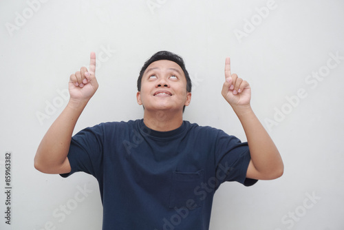 Asian man with shocked expression pointing his finger to copy space. people lifestyle concept. Asian male with t-shirt pointing, isolated on white background. photo