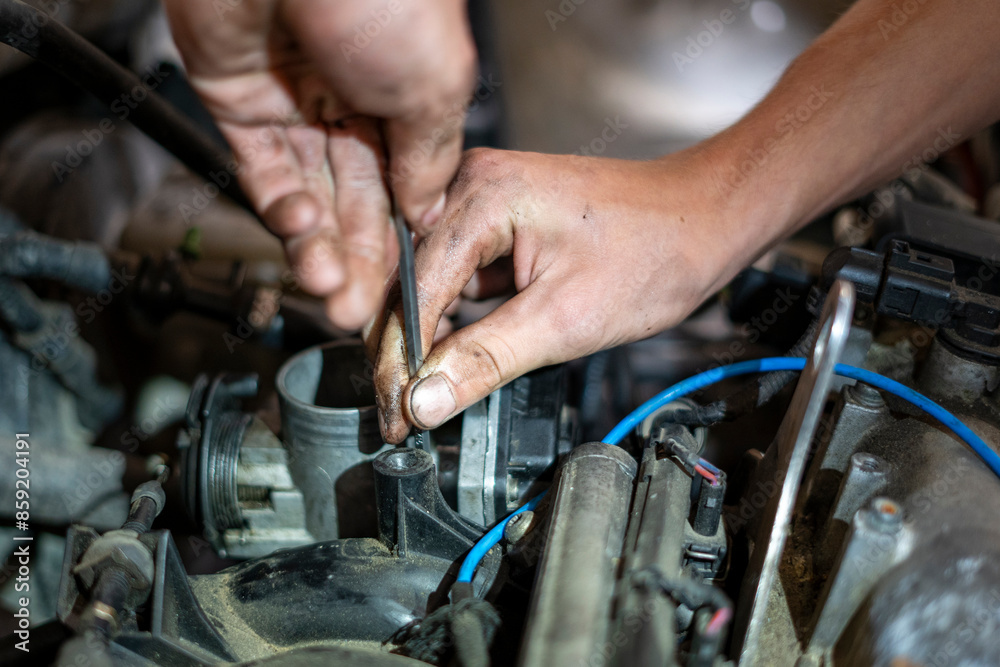 Car mechanic works on the engine of an old car Car mechanic works on the engine of an old car