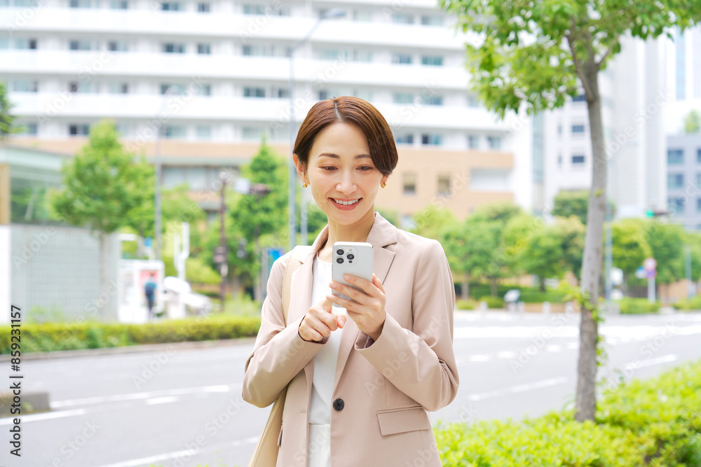 Fototapeta premium 外でスマートフォンを使うビジネスウーマン