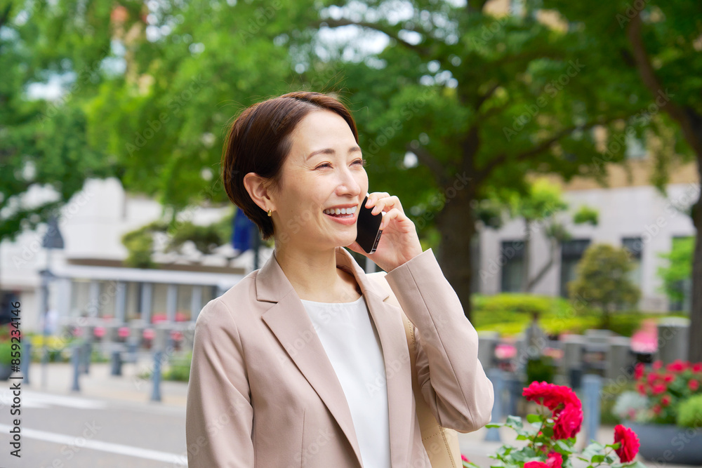 外でスマートフォンで電話をするビジネスウーマン 外でスマートフォンで電話をするビジネスウーマン