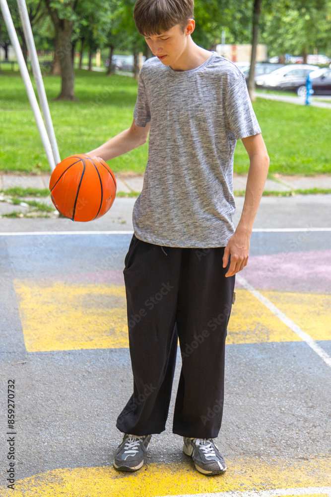 Young Boy Holding Basketball on Outdoor Court in Summer Young Boy Holding Basketball on Outdoor Court in Summer
