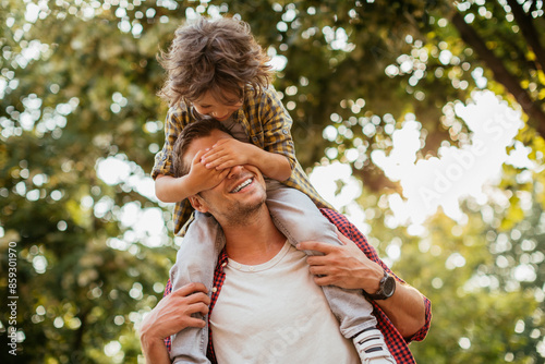 Joyful father giving piggyback ride to son on suburban street
