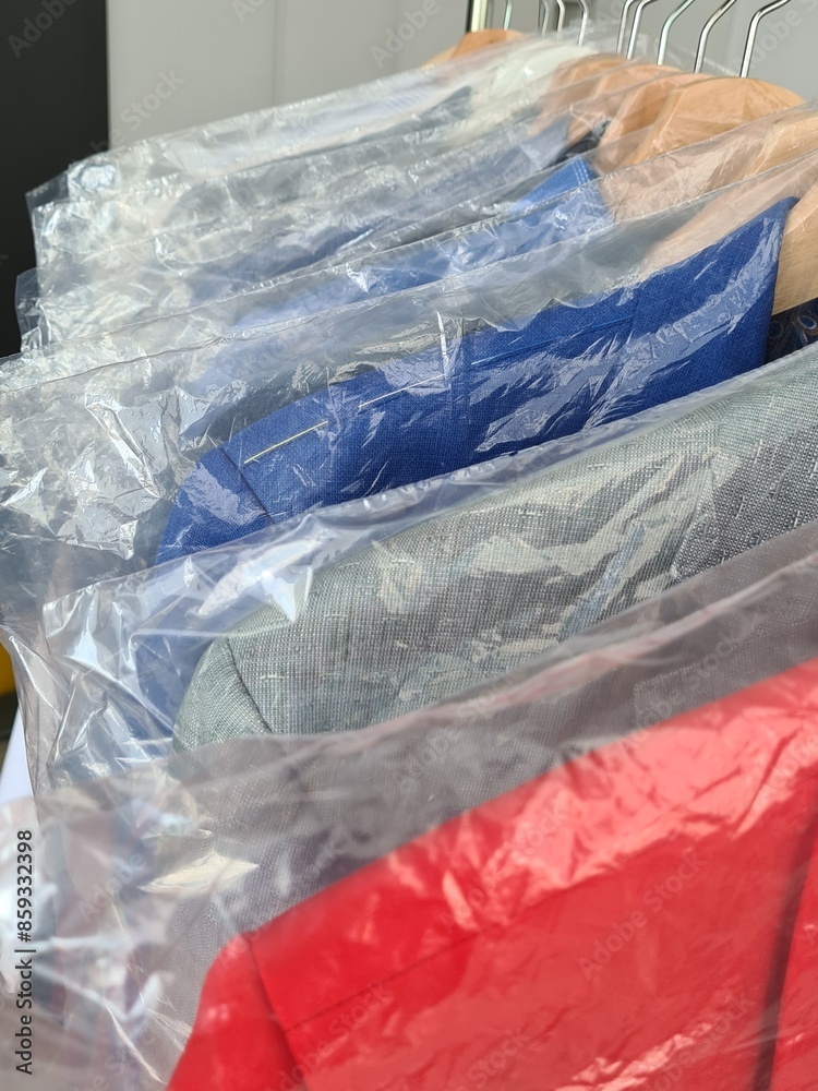 Obraz premium Stack of Cleaned and Wrapped Suits on Hangers in a Dry Cleaning Store