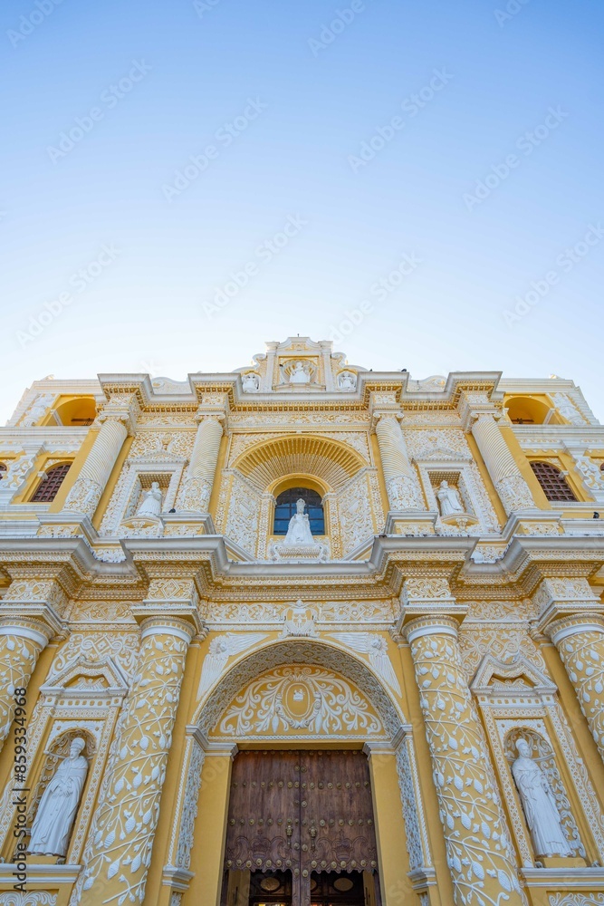 Obraz premium facade of catholic church with white patterns on yellow wall and saints