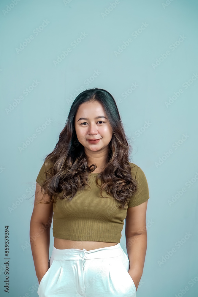 Portrait of a confident Asian woman smiling, standing looking at the camera isolated on a blue background Portrait of a confident Asian woman smiling, standing looking at the camera isolated on a blue background