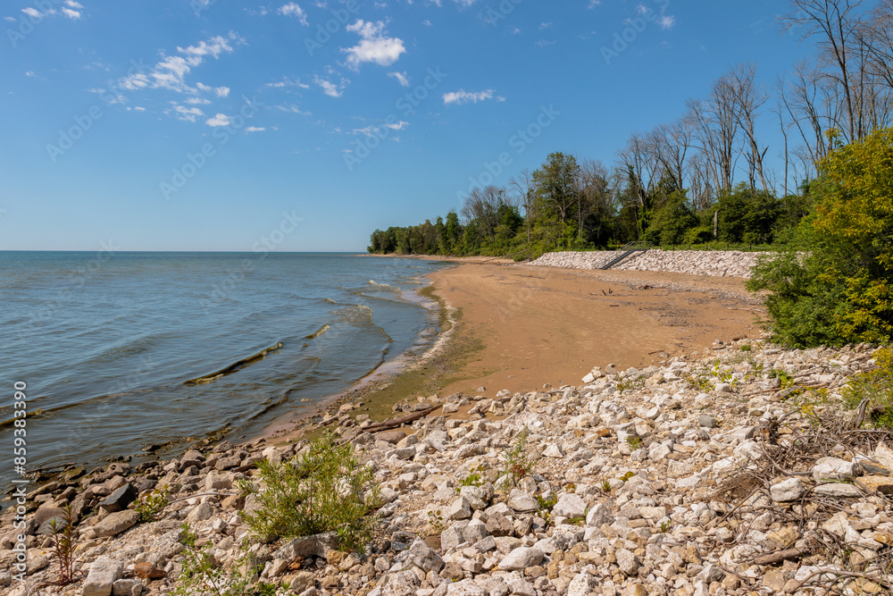 Looking south along the dog beach at Harrington Beach State Park, Belgium, Wisconsin in early June, under the blue sky with the calm Lake Michigan water casually touching the beach sand Looking south along the dog beach at Harrington Beach State Park, Belgium, Wisconsin in early June, under the blue sky with the calm Lake Michigan water casually touching the beach sand