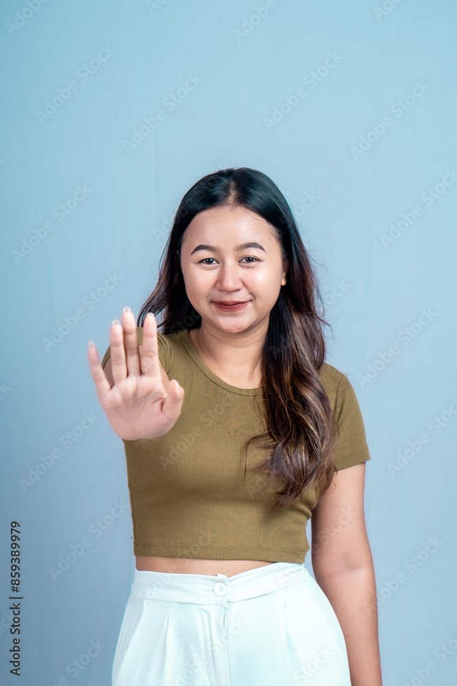 Young Asian woman wearing casual t-shirt over blue isolated background doing stop sign with palm of the hand. Young Asian woman wearing casual t-shirt over blue isolated background doing stop sign with palm of the hand.