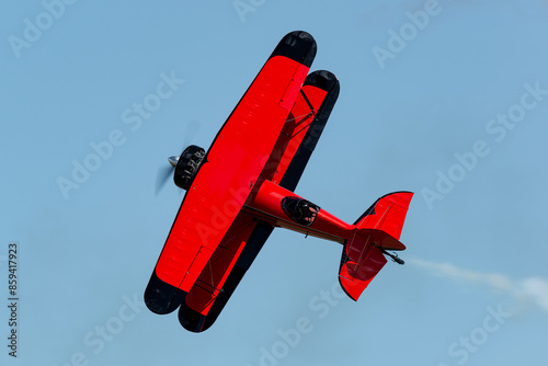 Photography Red bi-plane flying stunts during an airshow with smoke on