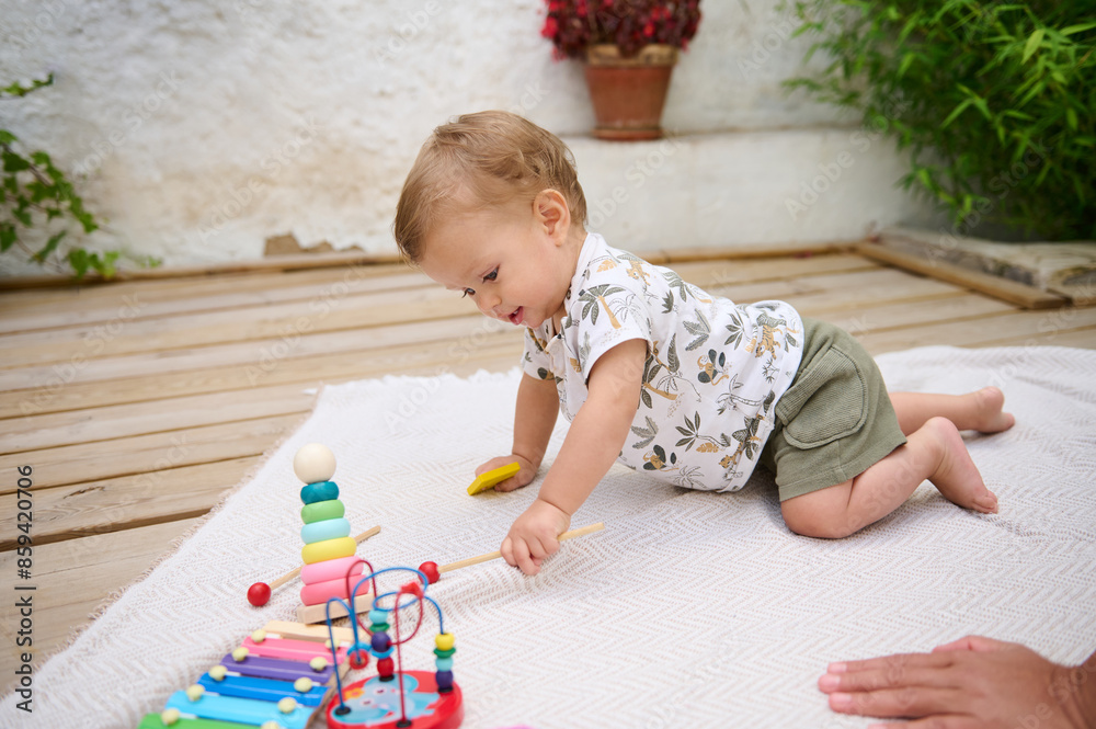 Cute baby playing with toys on a blanket outdoors Cute baby playing with toys on a blanket outdoors