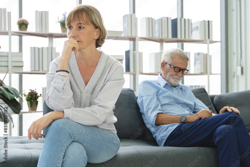 Sad mature woman sitting away from her husband after having quarrel Sad mature woman sitting away from her husband after having quarrel