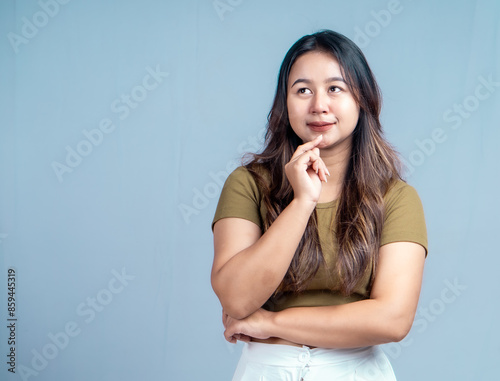 Young beautiful woman smiling joyfully and looking happy, feeling carefree and positive isolated by blue background © ajiilhampratama