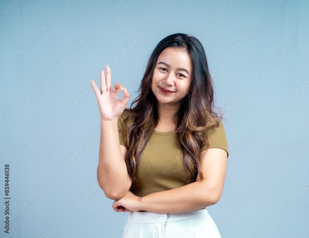 Fototapeta premium Young beautiful woman smiling joyfully and looking happy, feeling carefree and positive isolated by blue background