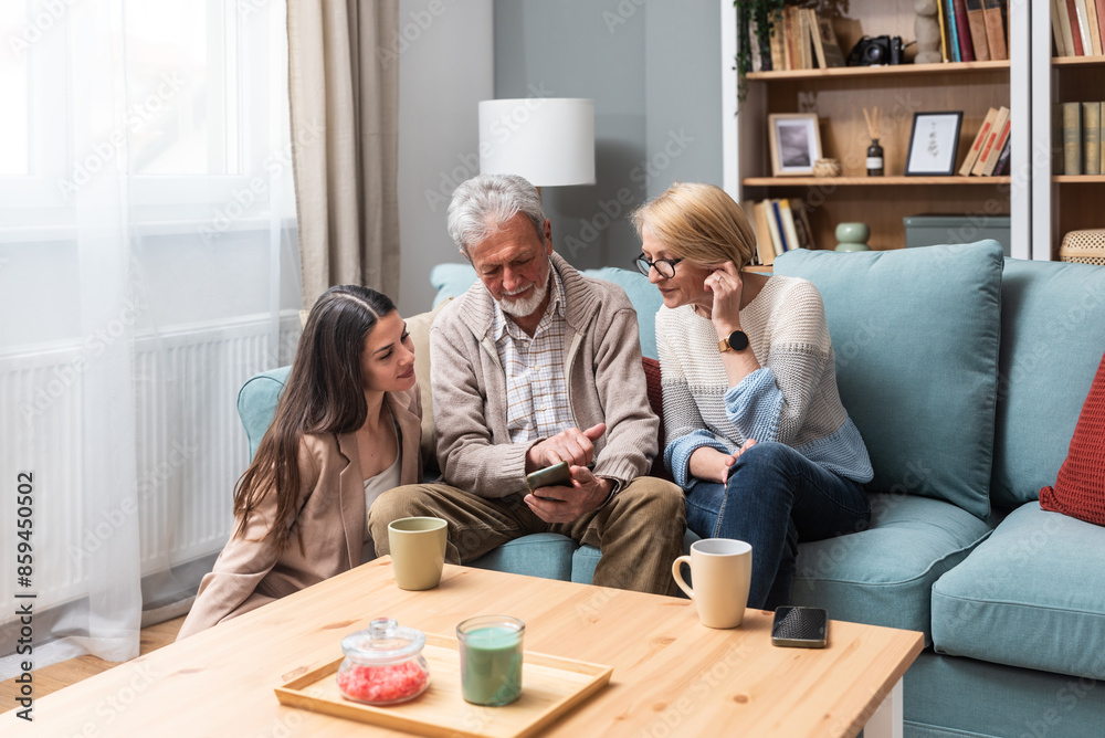 Simple living Mother father and daughter enjoying lovely time together at home. Senior couple and young woman in the apartment living room talking having fun on weekend activities during visit parents Simple living Mother father and daughter enjoying lovely time together at home. Senior couple and young woman in the apartment living room talking having fun on weekend activities during visit parents