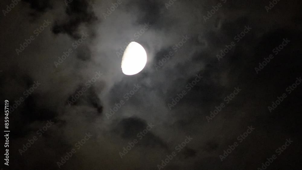 halfmoon shines through the clouds floating above the ground at night. halfmoon shines through the clouds floating above the ground at night.