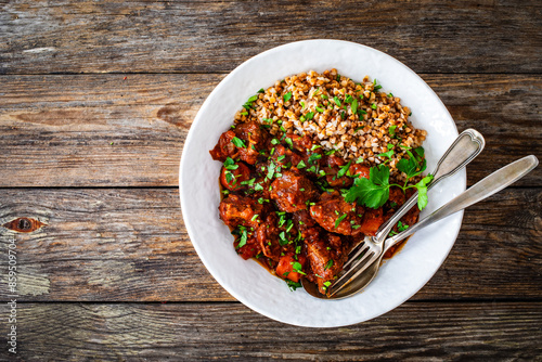 Roast beef with buckwheat groats and carrots served on wooden table
