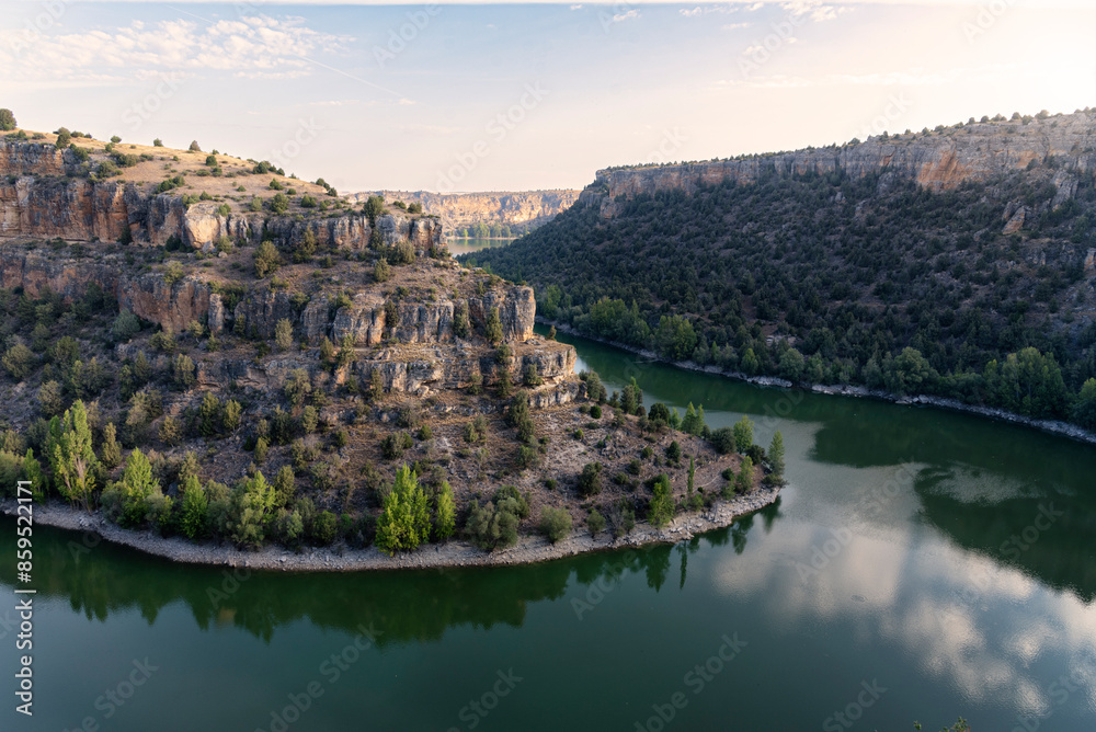 Duraton river runs through the rocky canyon while the water with green hue reflects the environment in a peaceful and serene scene, Duraton River Sickles Natural Park at sunrise, Sepulveda, Segovia, S Duraton river runs through the rocky canyon while the water with green hue reflects the environment in a peaceful and serene scene, Duraton River Sickles Natural Park at sunrise, Sepulveda, Segovia, S