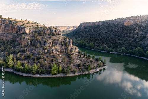 Duraton river runs through the rocky canyon while the water with green hue reflects the environment in a peaceful and serene scene, Duraton River Sickles Natural Park at sunrise, Sepulveda, Segovia, S