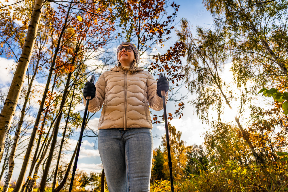 Nordic walking - one mid-adult beautiful woman exercising in city park using Nordic walking poles Nordic walking - one mid-adult beautiful woman exercising in city park using Nordic walking poles