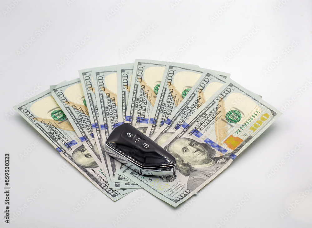 Modern car proximity key over the hundred dollar banknotes closeup. Modern car proximity key over the hundred dollar banknotes closeup.