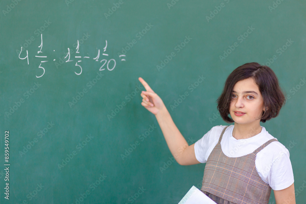 Beautiful girl at the blackboard solves a math problem Beautiful girl at the blackboard solves a math problem